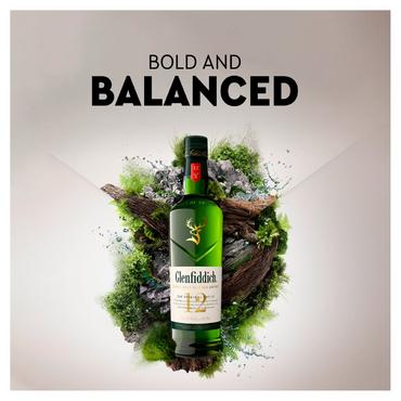 Бутилка 12-годишно скоч уиски Glenfiddich 1 л. на сив фон пред зеленина и дървен материал