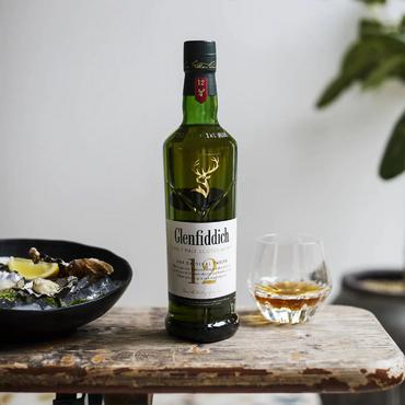 Бутилка 12-годишно скоч уиски Glenfiddich 1 л. върху маса с 1 чаша с уиски